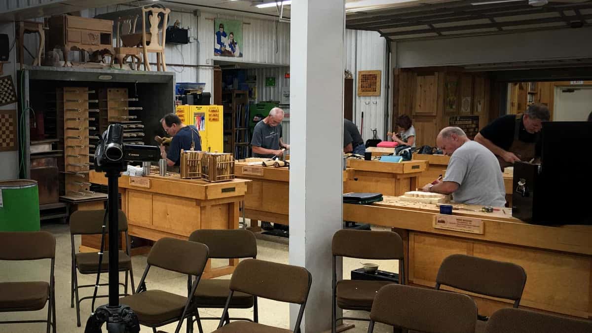Empty teaching shop, benches in rows, carvings on the far wall