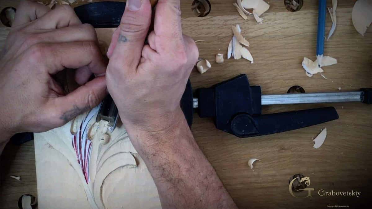 Two hands guiding a small tool over the drawn leaf