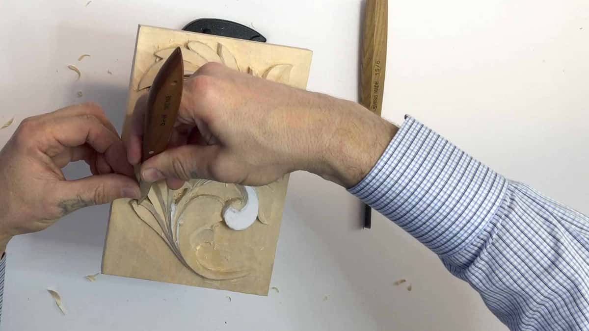 A wide chisel goes in with both hands behind it, and a Swiss gouge waits on the table
