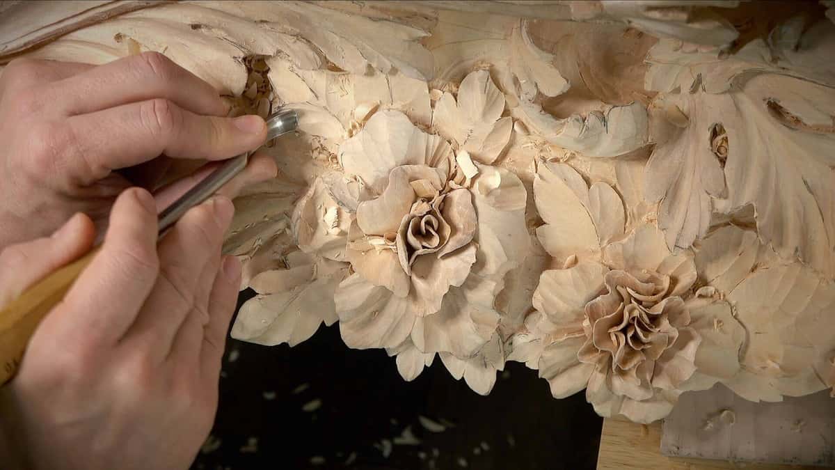 Carving basswood roses and leaves on a Venice Room panel with a gouge