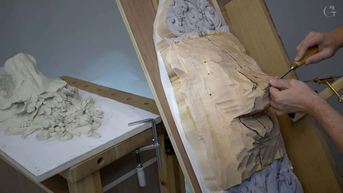 The clay model sits at the left while the same lion is cut into wood on the easel