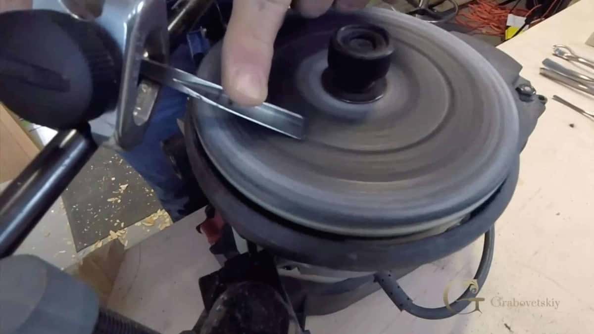 V tool laid flat on a spinning sharpening disc