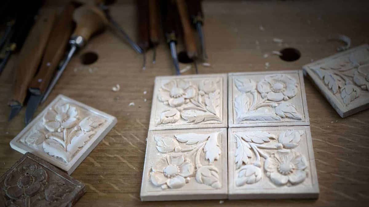 Six small carved rosette tiles laid out beside waiting gouges