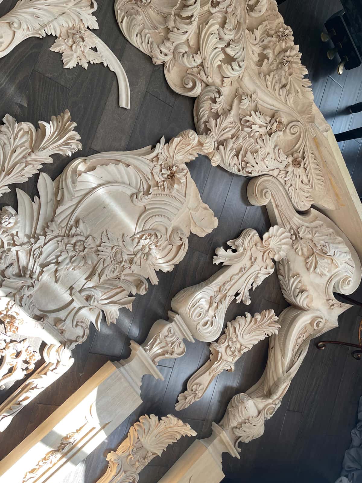 Finished Rococo panels, corbels and capitals for the Venice Room, laid out across a dark oak floor before painting
