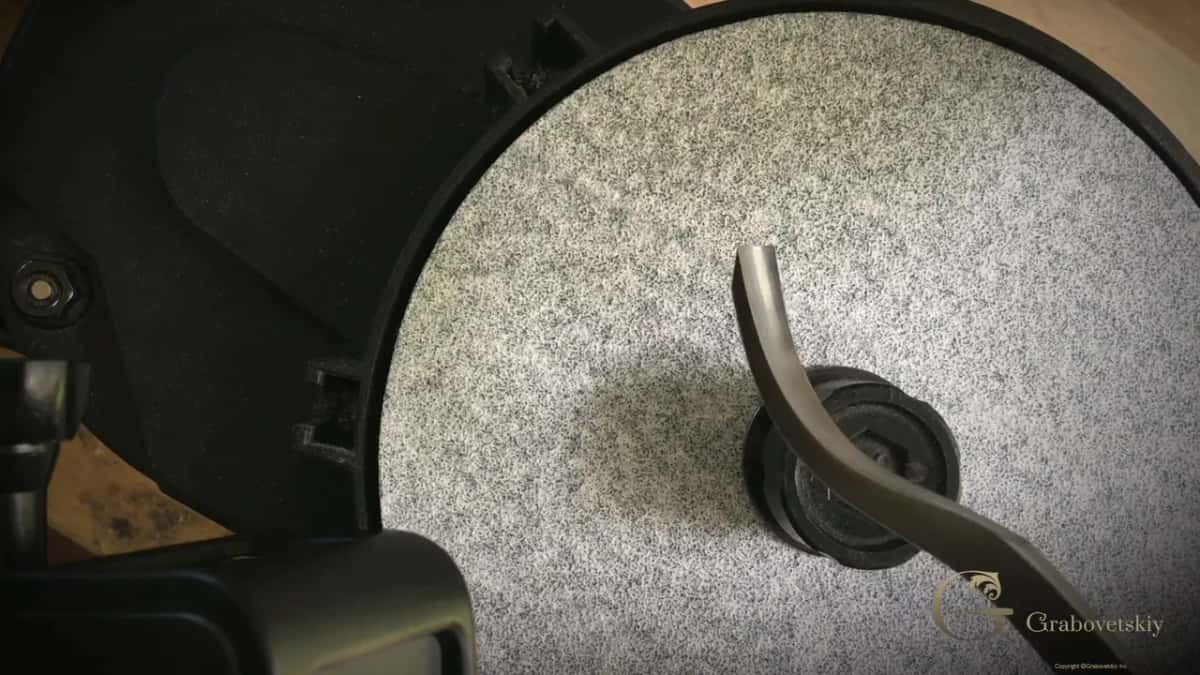 A bent gouge resting on a grey abrasive wheel inside its black guard, ready for honing hard wood.