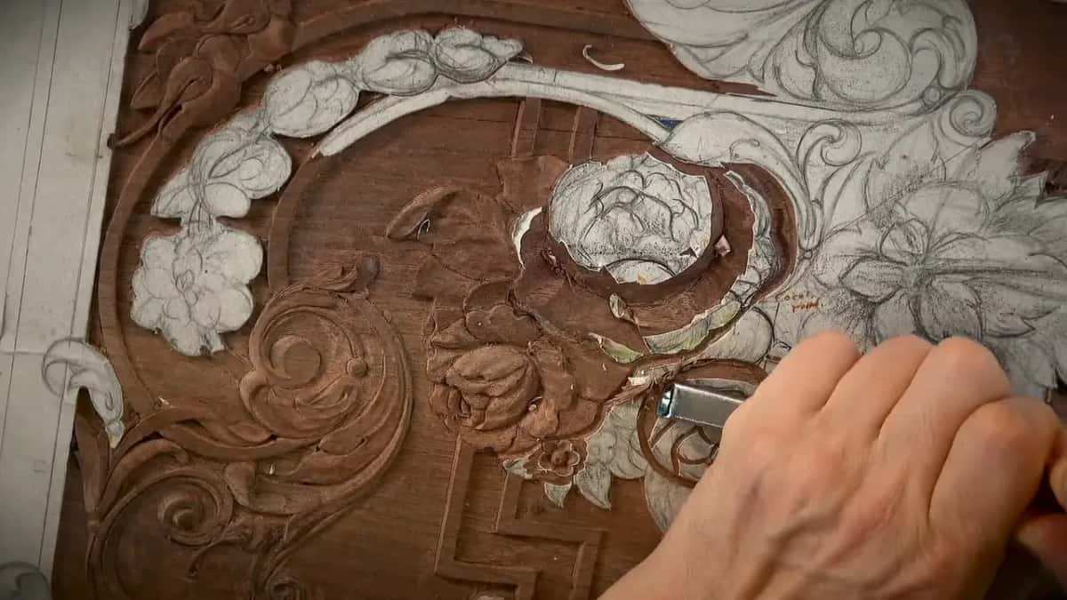 A round boss with a rose drawn on it stands in deep shadow on a reddish-brown relief panel.