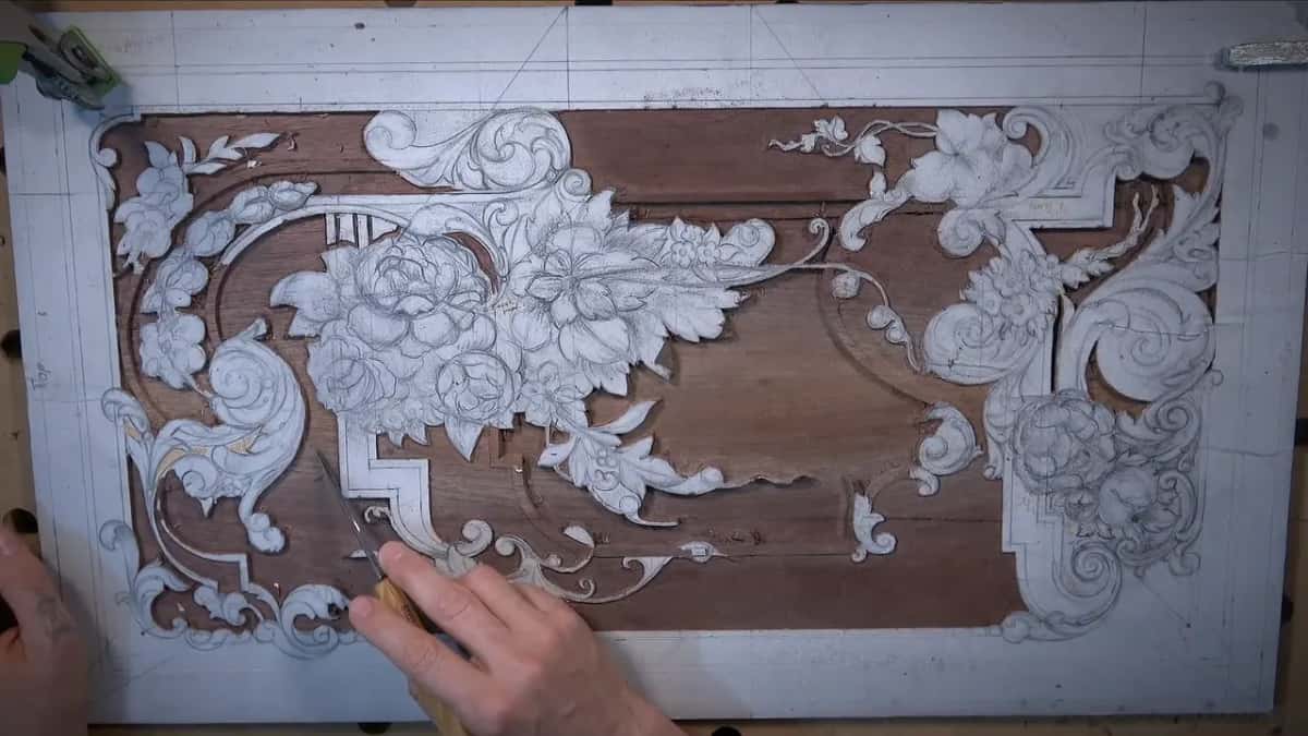 The same large panel further along, much more ground removed, a hand with a gouge at the lower left.