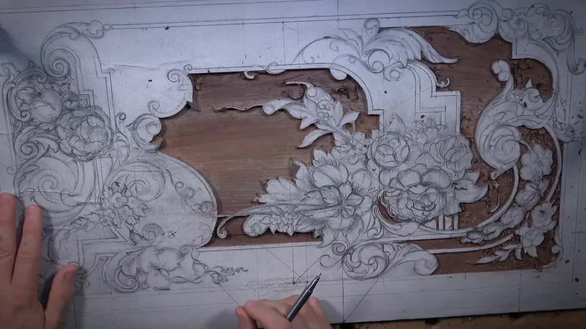 Overhead view of a large relief panel: the drawing still intact, the middle ground carved away to bare dark wood.