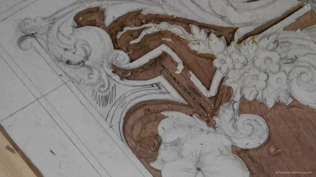 A stepped band of ground taken down to raw reddish wood between two drawn scrolls on a panel.