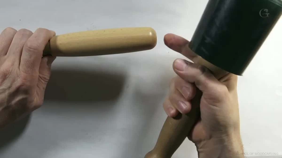 Round carving mallet held next to a plain wood handle, both held still rather than in use.
