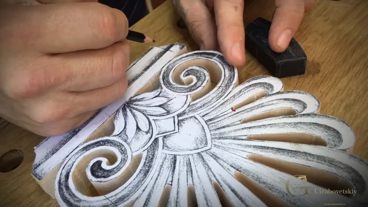 Holding a pencil above the pasted pattern, ready to mark another line across the two scrolls.