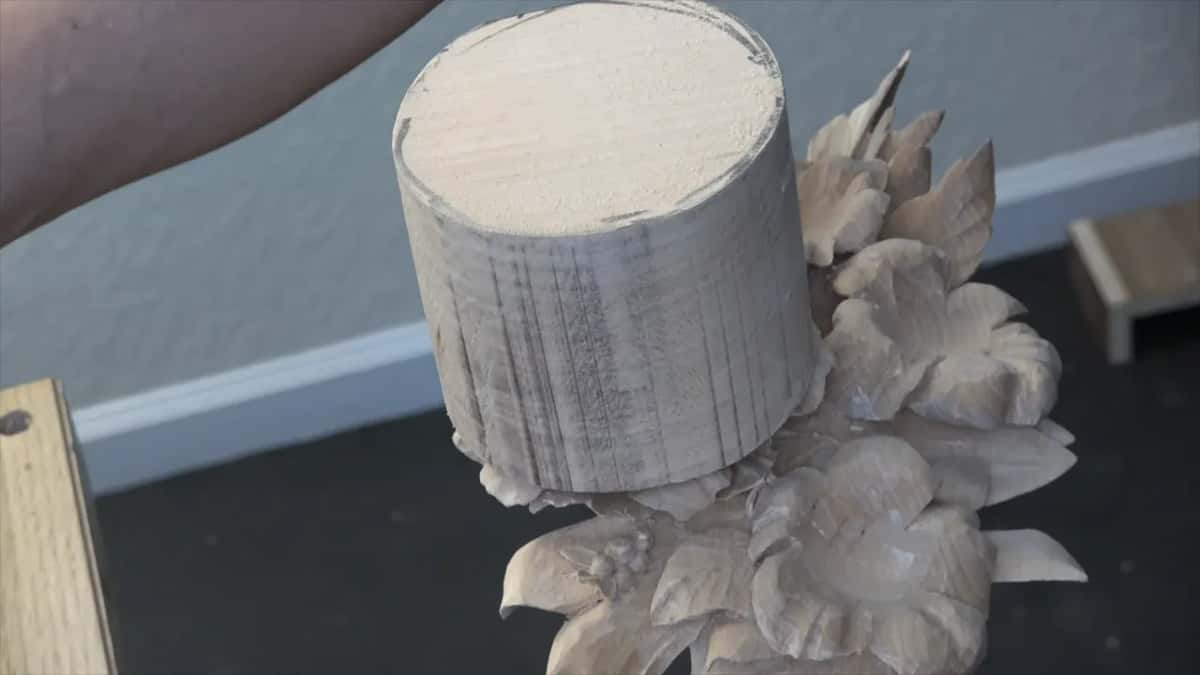 Standing on top of finished carved flowers, a tall round blank holds the height still to be worked.