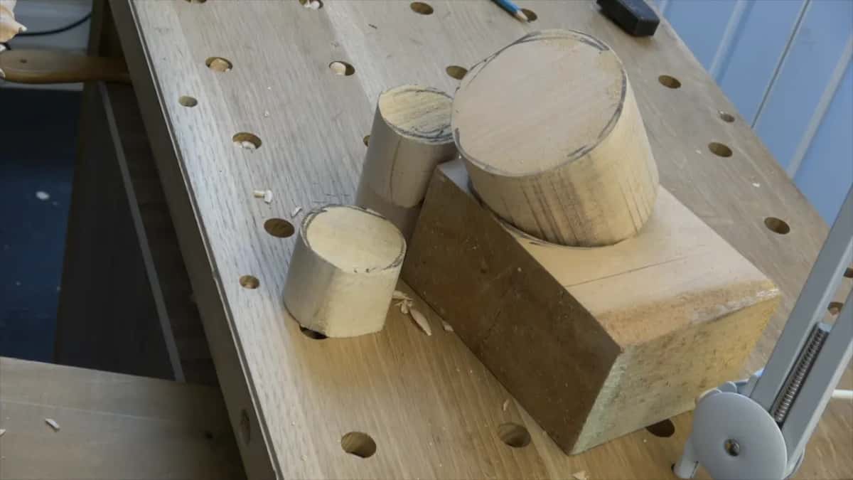 Round blanks and a thick squared block sit together on the bench, each one a different height.