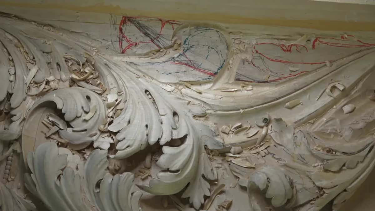 Acanthus leaves carved deep fill this panel, with red and blue drawing still on the wood above.