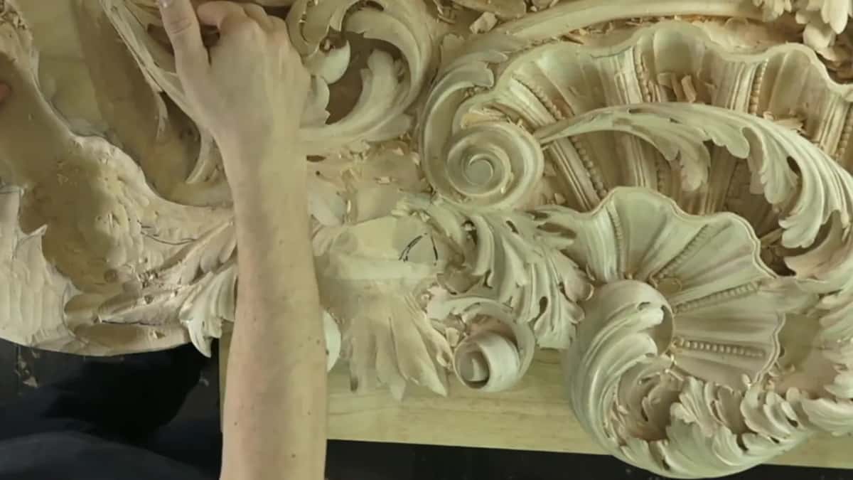 Looking down a long panel, the shell and scrolls sit in layers deep enough to hide their own edges.
