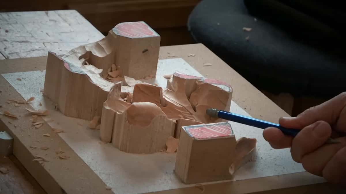 Tall blocks and low hollows sit side by side in a roughed out relief, with a pencil pointing in.