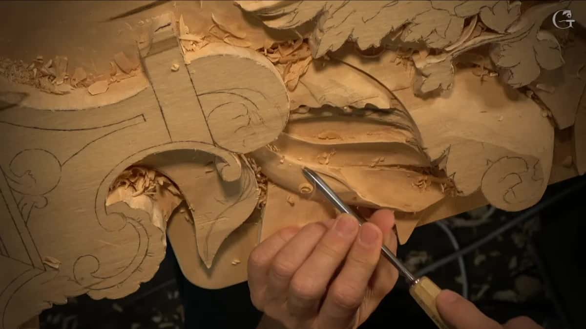 A slim tool points into the dark gap carved under a pale leaf, lifting it clear of the background.