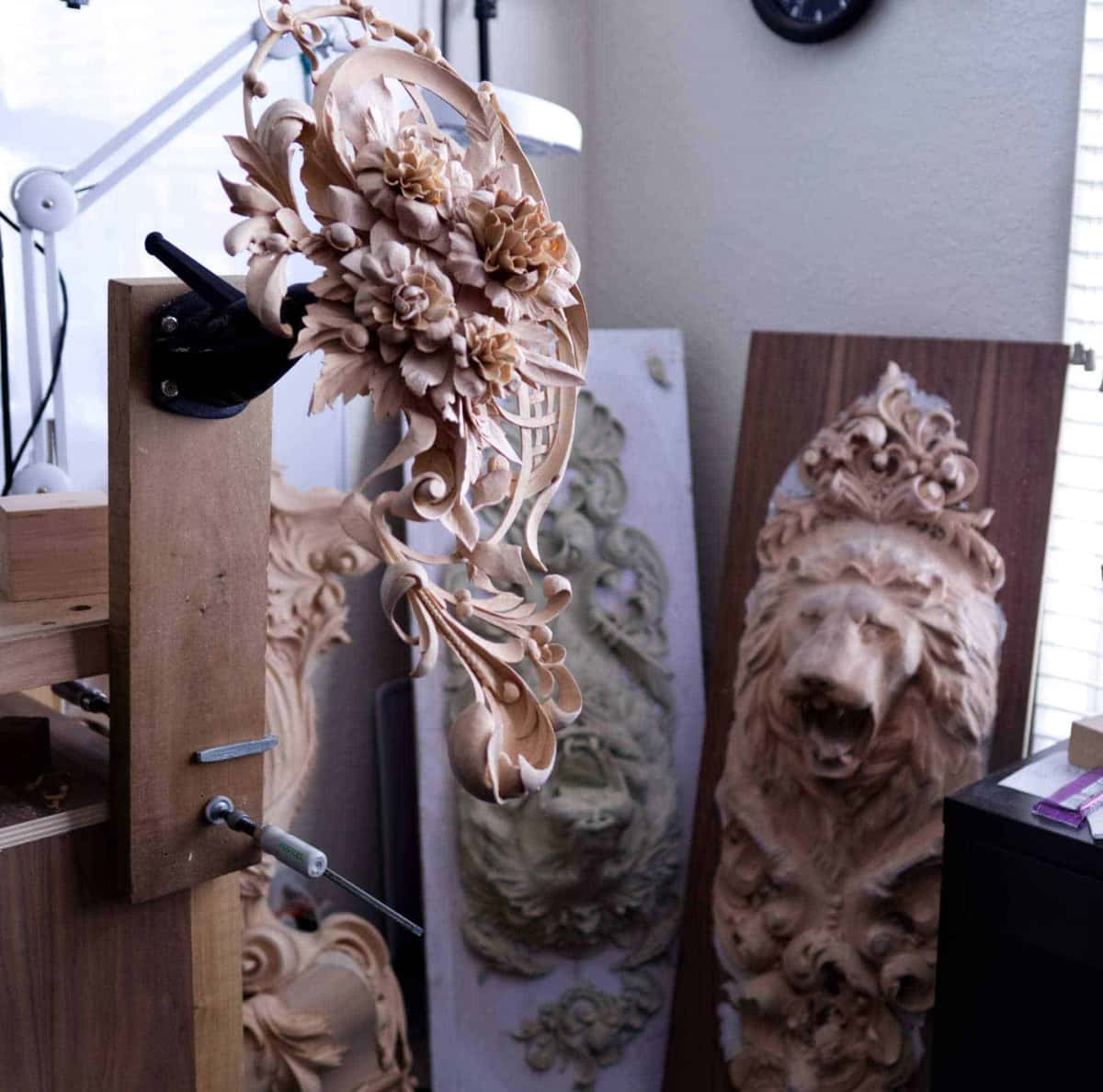 An oval rosette clamped in the vise, the lion boards leaning against the wall behind it