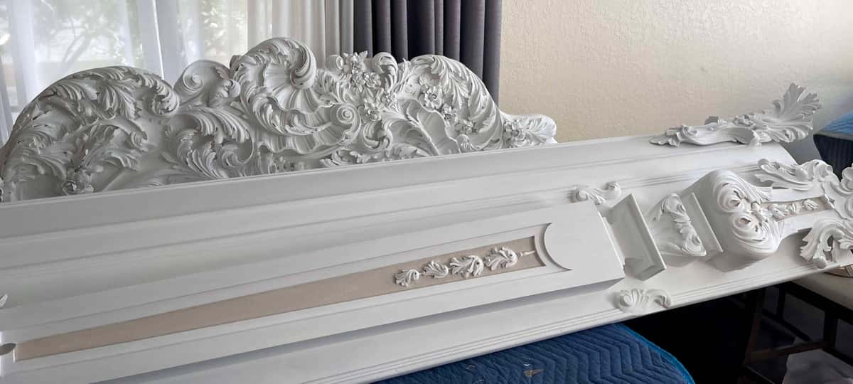 The same cornice after paint: a white shell crest riding a run of acanthus