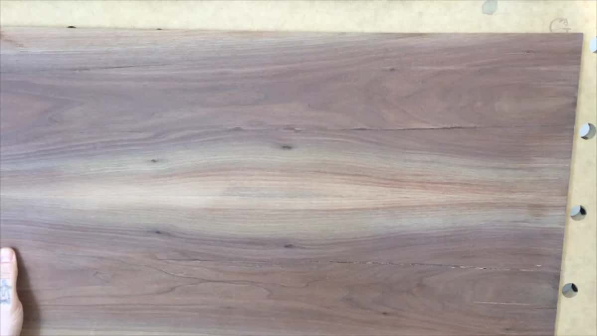 A wide dark purple-brown board fills the frame, its figure sweeping in long waves down the length.