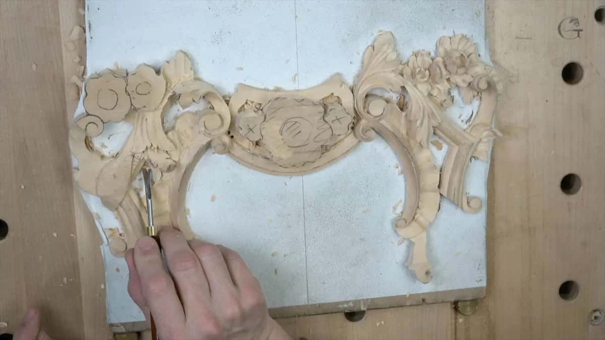 White painted panel carries a symmetrical cartouche of scrolls and blossoms part way carved