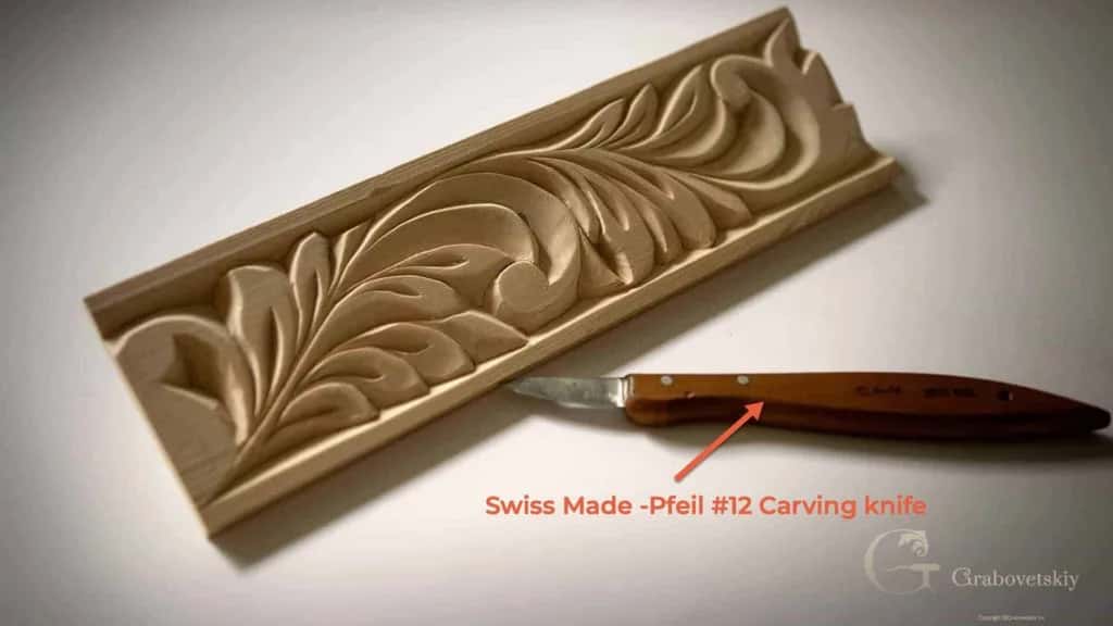 A carved acanthus moulding lying beside the Pfeil number 12 chip carving knife that cut it