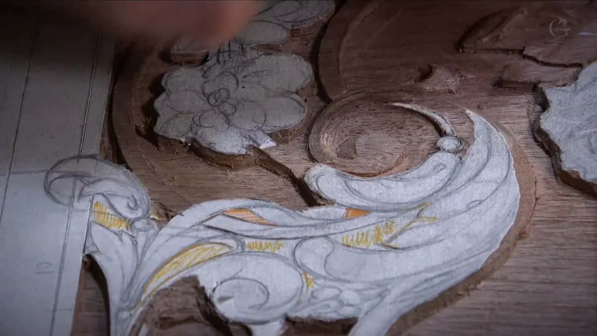 A deep round hollow carved into a reddish panel beside a drawing marked up in yellow and grey pencil.