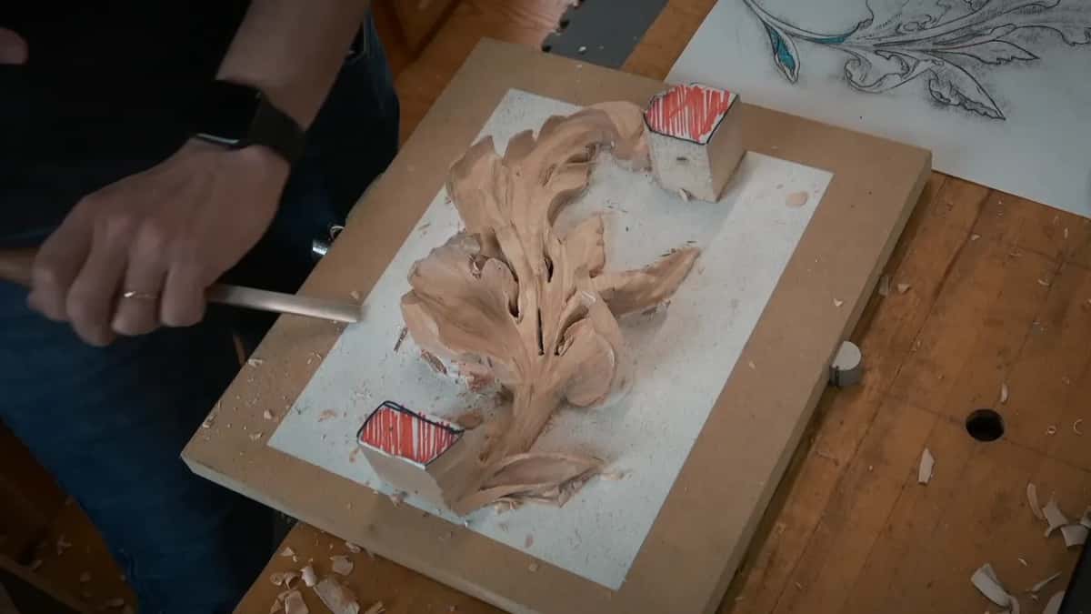 An acanthus spray carved on a board screwed to MDF, waste blocks left standing with their tops marked red.
