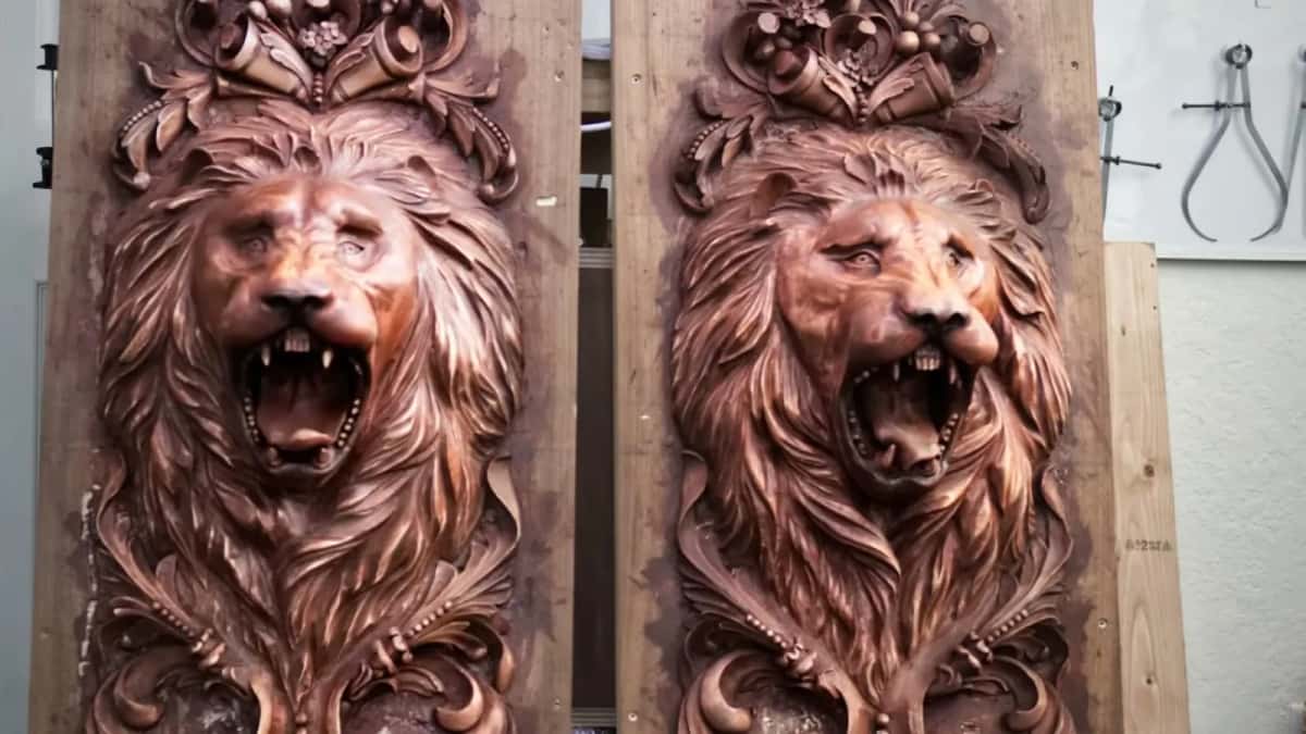 Staves, not one block Two matching carved lion head panels standing against the shop wall, with the glue lines just visible