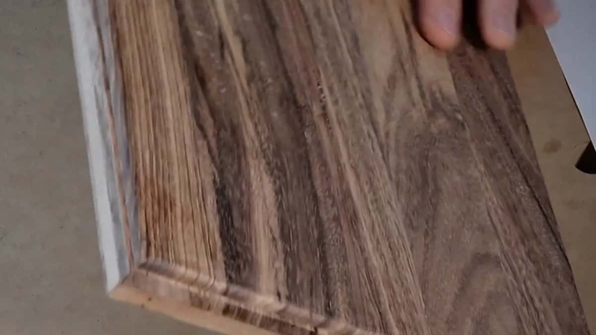 Close view of a board face, pale gold and dark brown streaks running its length, with a rounded-over front edge.