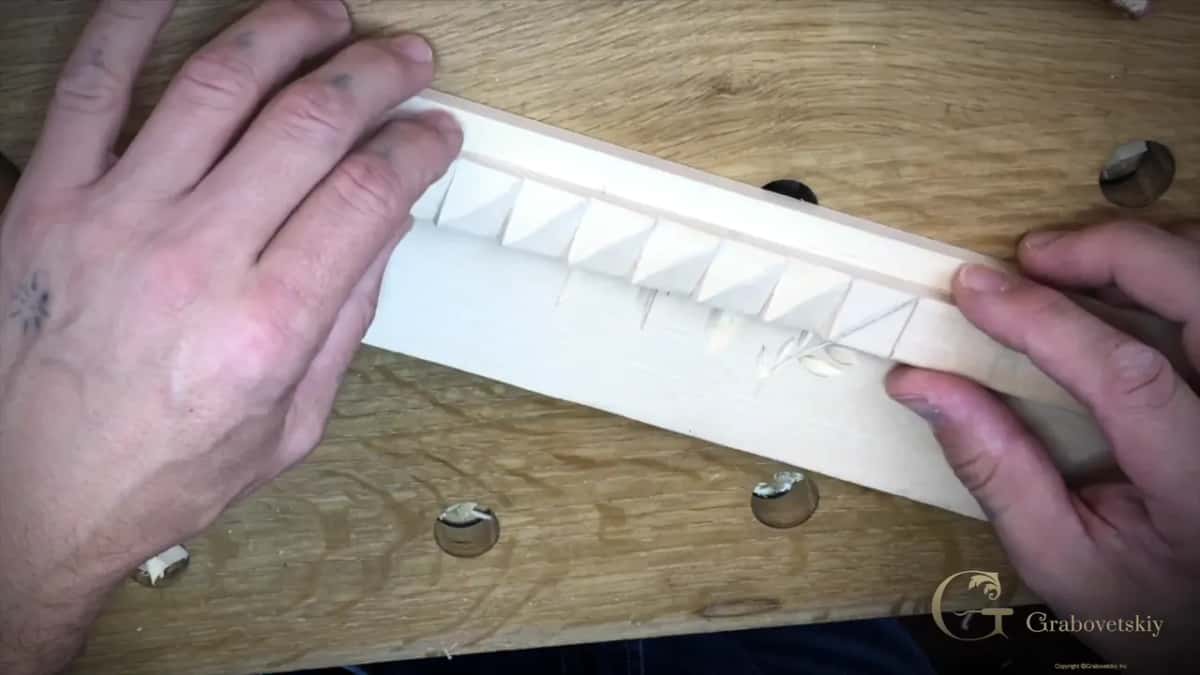 Finished hand carved molding held up so the shadow shows how deep each space goes